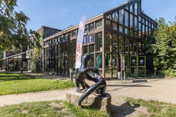 A modern building with large glass windows and a sculpture in front.