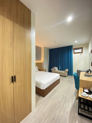 A hotel room with a large wardrobe, a bed, a desk, and a sofa. - Vanyard Hotel (Kalibo)