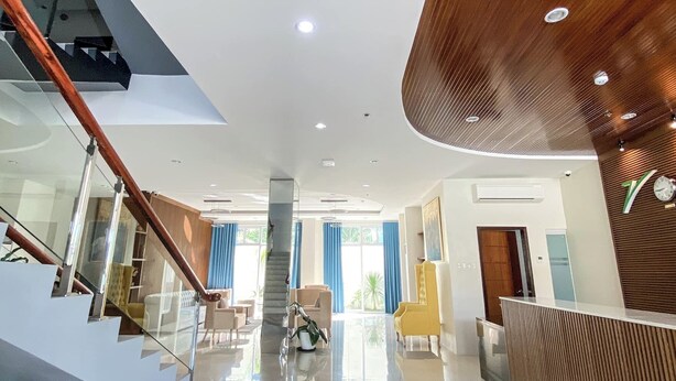 Eine großzügige Lobby mit einer modernen Treppe, einem Empfangsbereich und einem großen Fenster mit blauen Vorhängen.
