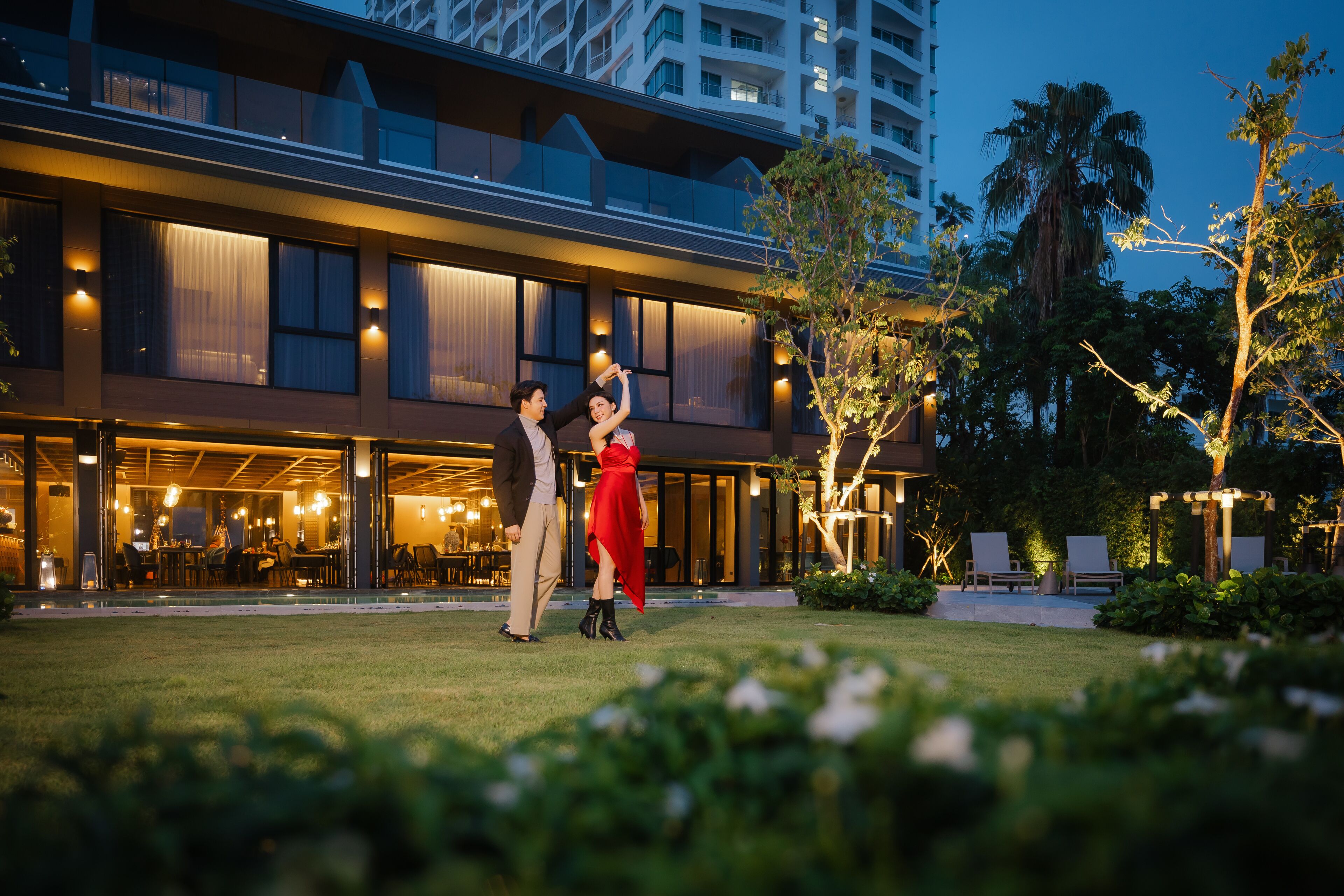 A hotel with a modern design, featuring a spacious outdoor area with a pool and lounge chairs.