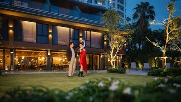 A hotel with a modern design, featuring a spacious outdoor area with a pool and lounge chairs.