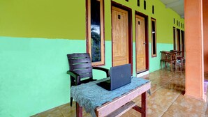A room with a green wall, wooden doors, a laptop on a table, and a chair. - Hotel O Anisah Adil Homestay SyariahNearsmart Kampung Desa Pakistaji (Banyuwangi)