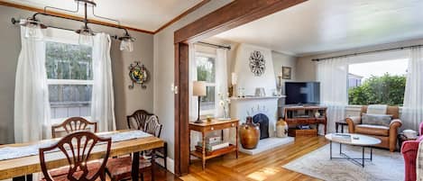 A spacious living area with a wooden dining table, chairs, a sofa, and a television.