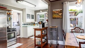 Une cuisine moderne avec des meubles blancs, une cuisinière en acier inoxydable et un coin repas comprenant une table et des chaises en bois.