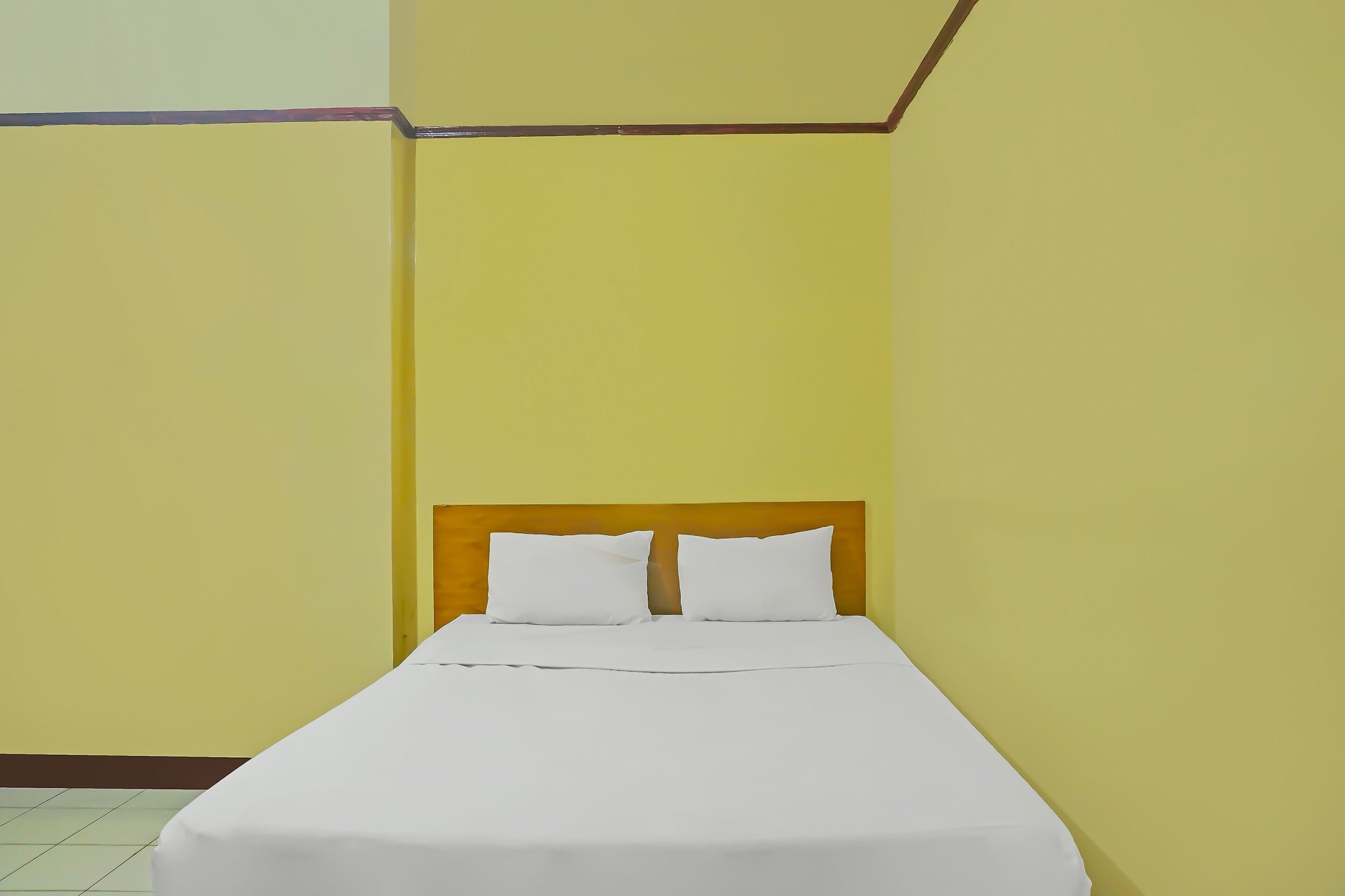 Ein Einzelbett mit Holz-Kopfstück in einem Zimmer mit gelben Wänden.