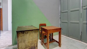 Una habitación con una pared verde, una mesa de madera, una silla de madera y una puerta gris.