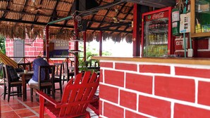 Un restaurant aux murs en briques rouges, avec une chaise rouge et un réfrigérateur Coca-Cola.