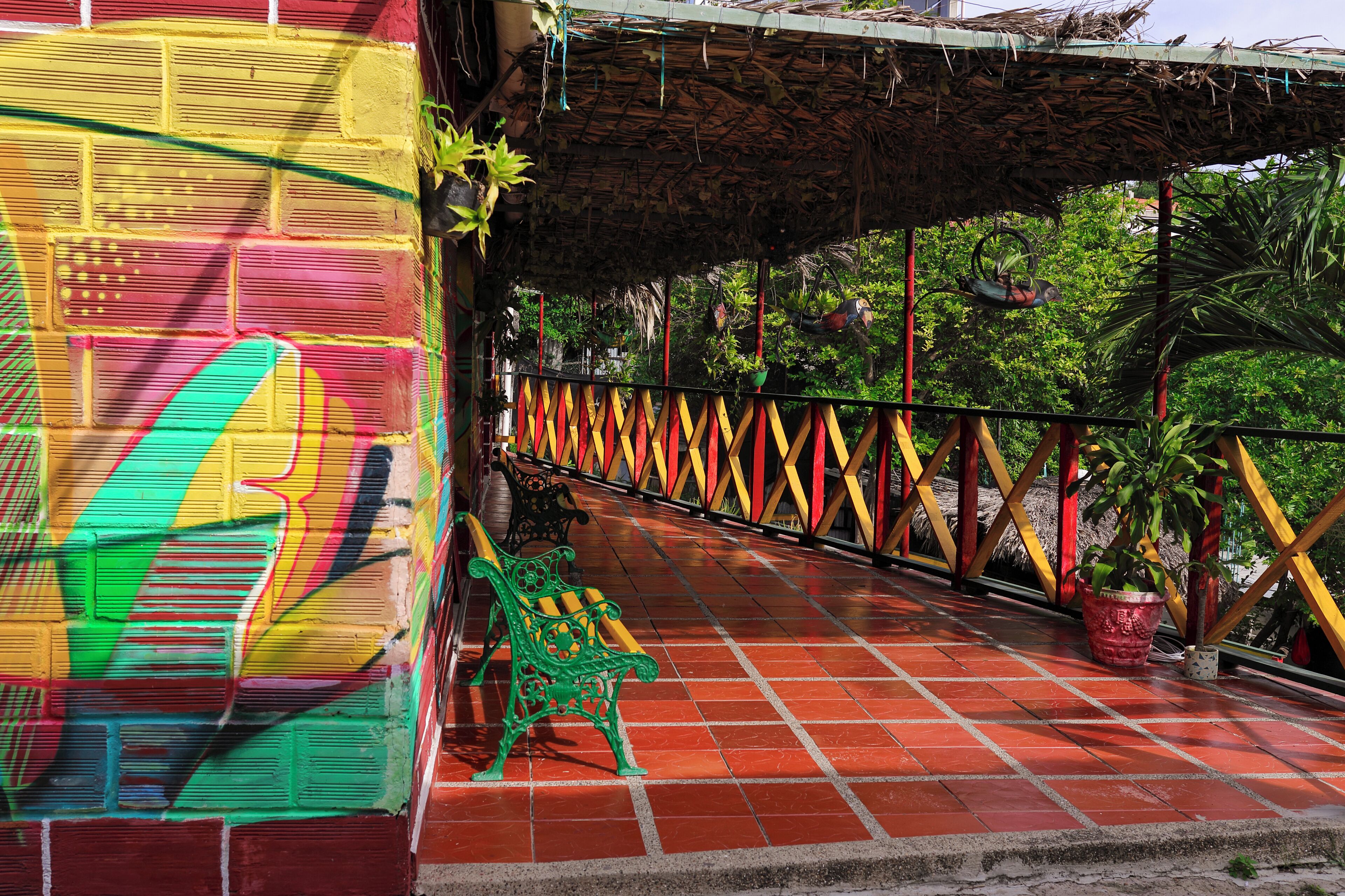 A colorful outdoor area with a tiled floor, a green bench, and a decorative fence.