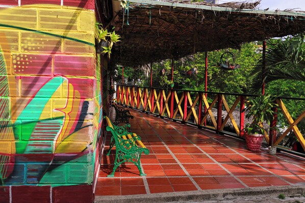 Un espace extérieur coloré, doté d’un sol carrelé, d’un banc vert et d’une clôture décorative.