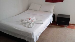Un lit bien fait, avec du linge de lit blanc et une serviette posée sur le lit.