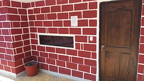 Un mur en briques rouges avec une porte en bois et une petite fenêtre.