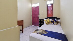 Una habitación pequeña y limpia con una cama, un escritorio y dos puertas.