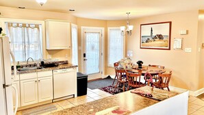 A kitchen with white cabinets, a dining table with chairs, a chandelier, and a painting on the wall. - Family & pet-friendly, peaceful rural escape. Hiking nearby. (Harding)