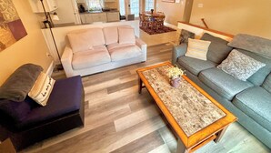 A spacious living room with a large beige sofa, a grey sofa, and a wooden coffee table. A dining area with a red rug and chairs is visible in the background. - Family & pet-friendly, peaceful rural escape. Hiking nearby. (Harding)