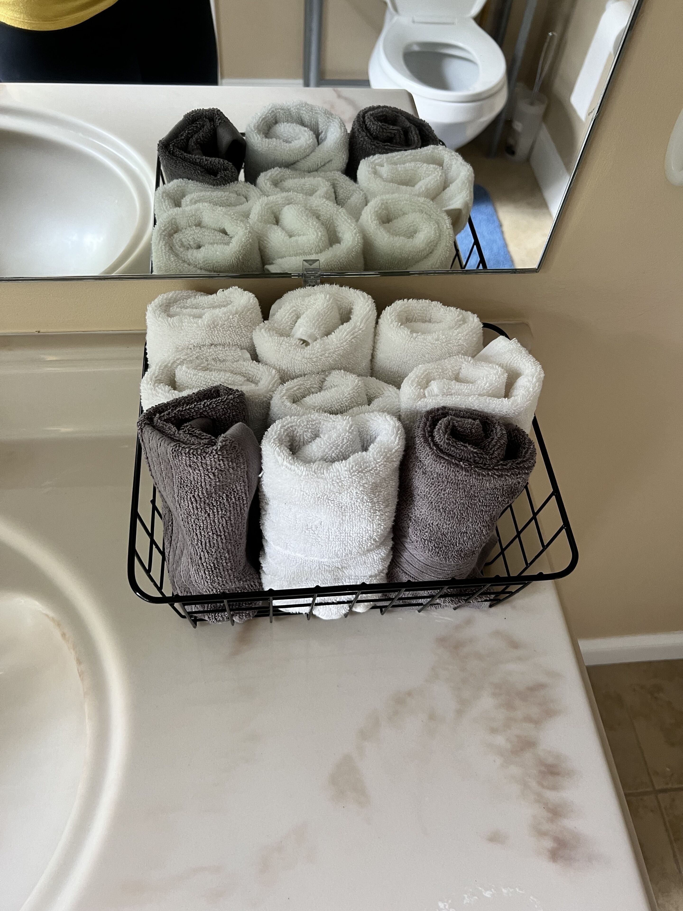 A bathroom with a towel rack holding neatly folded towels in various colors.