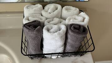 A bathroom with a towel rack holding neatly folded towels in various colors.