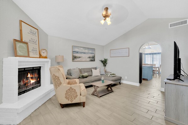 A living room with a fireplace, a sofa, a coffee table, and a television.