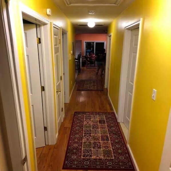 A narrow hallway with wooden flooring and a patterned rug.