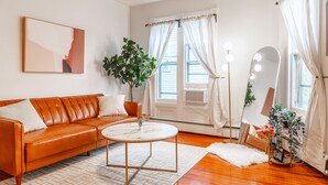 Un salon moderne avec un canapé en cuir, une table basse ronde et un grand miroir avec éclairage intégré.