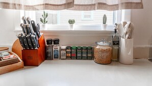 Un plan de travail de cuisine avec différentes épices, un pot de sucre et un bloc à couteaux.