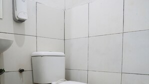 A small bathroom with a toilet, a sink, and a hand dryer. The floor has a patterned tile design. - Hotel O Penginapan Raja (Sukabumi)