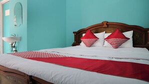 A bed with a wooden headboard, white bedding, and red pillows. - Hotel O Penginapan Raja (Sukabumi)