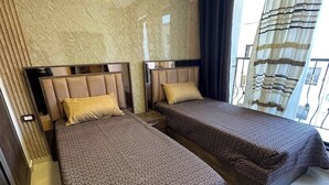 A hotel room with two beds, a marble wall, and a view of the outside.
