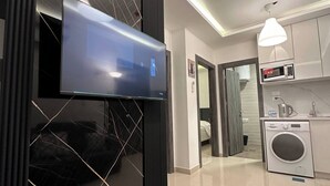 Una cucina moderna con forno a microonde, lavatrice e televisore a schermo piatto montato su una parete nera.