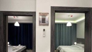 Una camera d'hotel con un letto, un comodino, una lampada, uno specchio e una luce a soffitto.