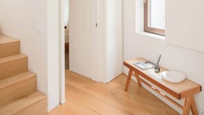 A modern interior with a wooden staircase, a white door, a window, and a wooden table with a sink.