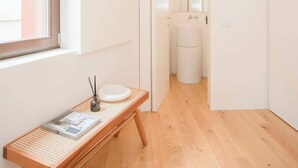 A modern, minimalist bathroom with a wooden floor, a white sink, and a large mirror.