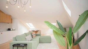 A modern loft apartment with a green sofa, a small side table, and a large plant.