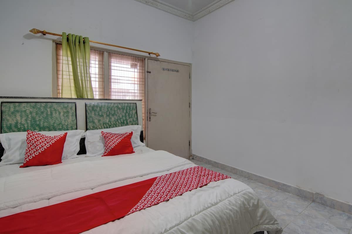 A bedroom with a bed, a wardrobe, and a window with curtains.