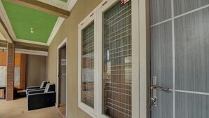 A hallway with a green ceiling, a door with a metal handle, and a window with a grid pattern. - OYO 92833 Penginapan Syariah (Pekanbaru)