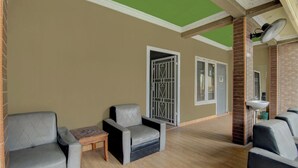 A room with two grey armchairs, a small wooden table, a green ceiling, and a brick wall. - OYO 92833 Penginapan Syariah (Pekanbaru)