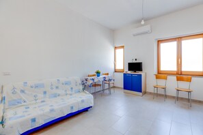A room with a sofa, a TV, a table with chairs, and a window. - Holiday Home 'Casa Simo' with Sea View, Wi-Fi and Air Conditioning (Porto Alabe)
