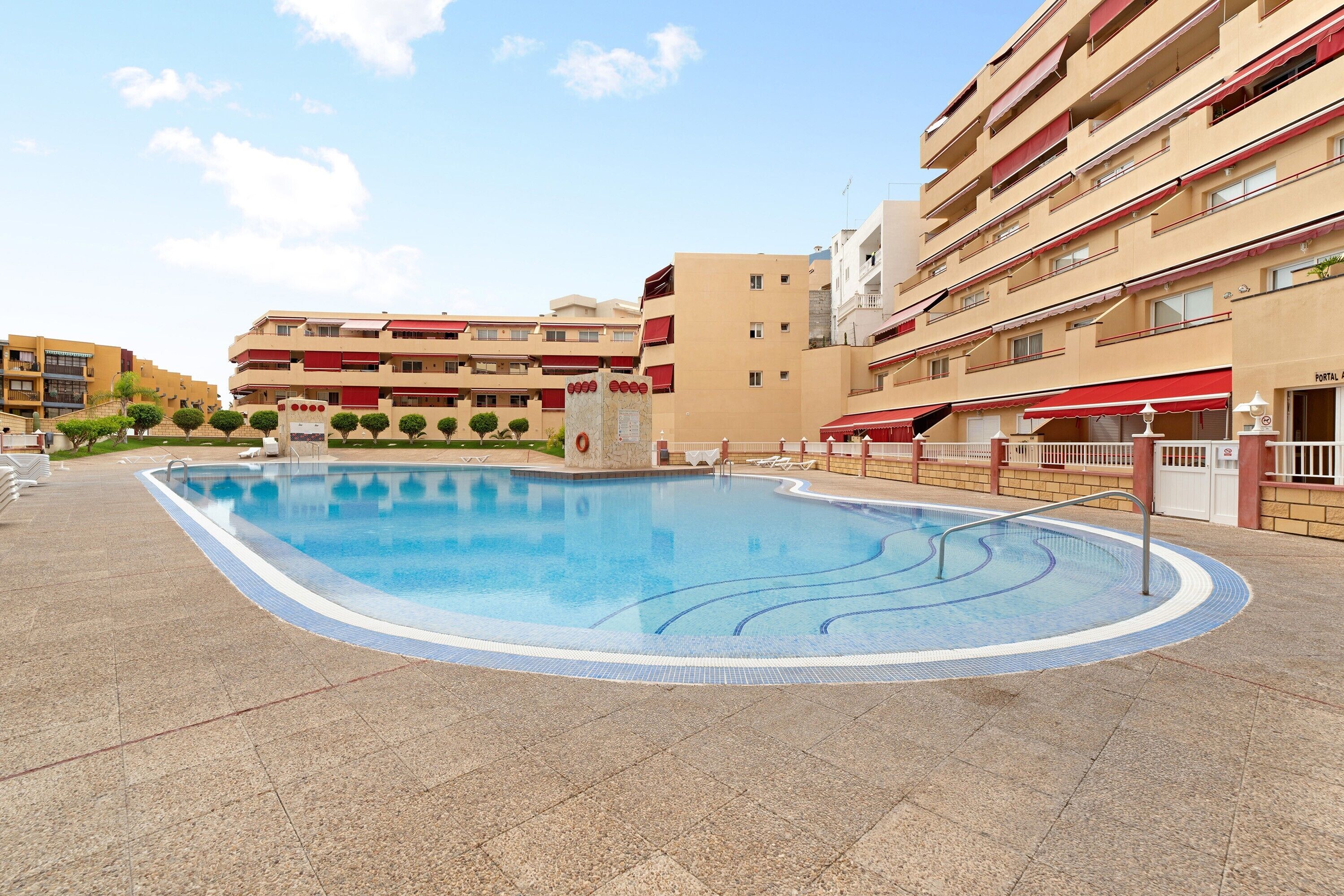 Una piscina con bordo piastrellato, circondata da edifici a più piani con balconi.