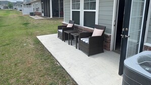 Propiedad residencial con patio cubierto, mobiliario exterior y una parrilla.