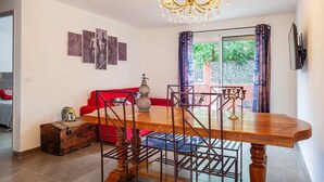 A dining area with a wooden table, metal chairs, a chandelier, and a red sofa.