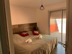 Camera da letto con un letto, cuscini, testiera, una porta e vista attraverso una porta vetrata.