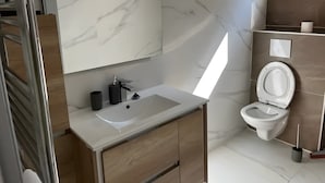 Ein modernes Badezimmer mit einem Marmor-Waschtisch, einer Toilette und einem Bidet.
