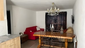 Ein Essbereich mit einem Holztisch, einer roten Couch und einer Chandelier.