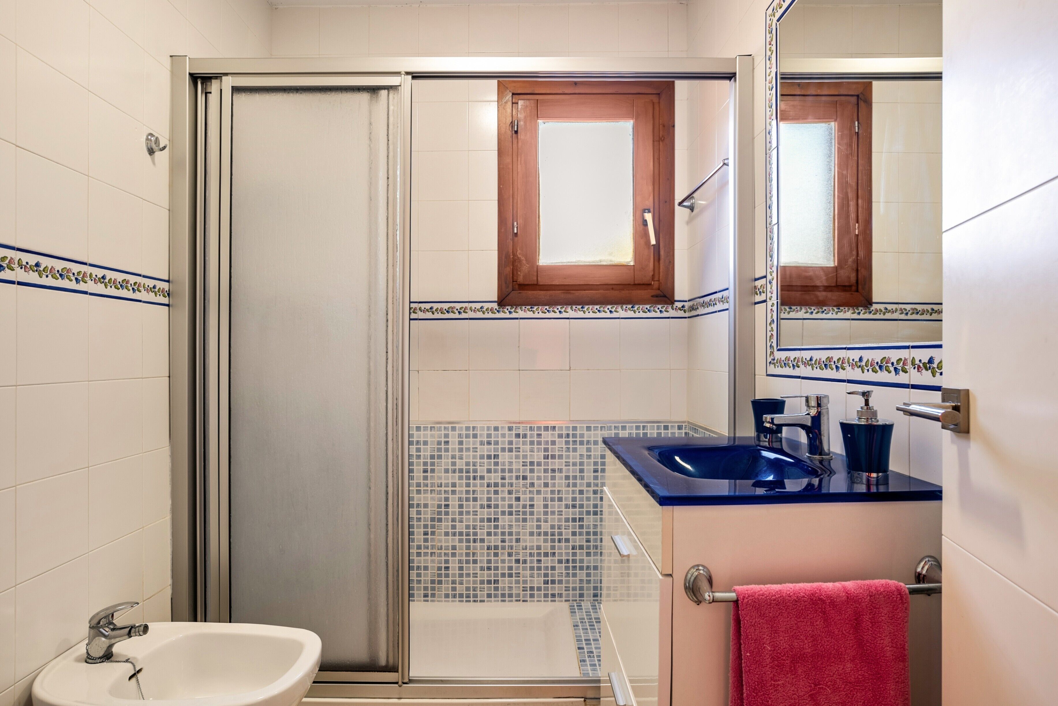 A bathroom with a shower, sink, and mirror.