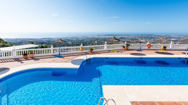 Ein Pool mit Blick auf die Stadt, ein weißer Zaun und Kübelpflanzen.