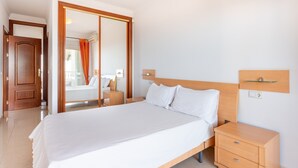 Ein Hotelzimmer mit einem großen Bett, einem Holzkopfstück, Nachttischen und Blick durch eine Schiebetür.