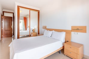 Habitación de hotel con una cama grande, cabecera de madera, mesitas de noche y vistas a través de una puerta corredera.