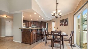 A spacious kitchen with dark wooden cabinets, a central island, and a dining area with a table and chairs. - Lakefront Gem • Boat Rental • Sleeps 8 people (Discovery Bay)