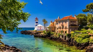 A coastal building with a lighthouse, clear blue sea, and rocky shoreline. - Lovely & Comfy 3 – Apartment near the beach in Estoril for up to 4 guests (Estoril)