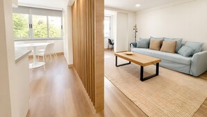 A modern living room with a sofa, a coffee table, and a dining area with chairs. - Lovely & Comfy 3 – Apartment near the beach in Estoril for up to 4 guests (Estoril)
