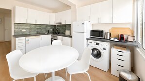 A compact kitchen with white cabinetry, a built-in oven, a microwave, and a washing machine. - Lovely & Comfy 3 – Apartment near the beach in Estoril for up to 4 guests (Estoril)